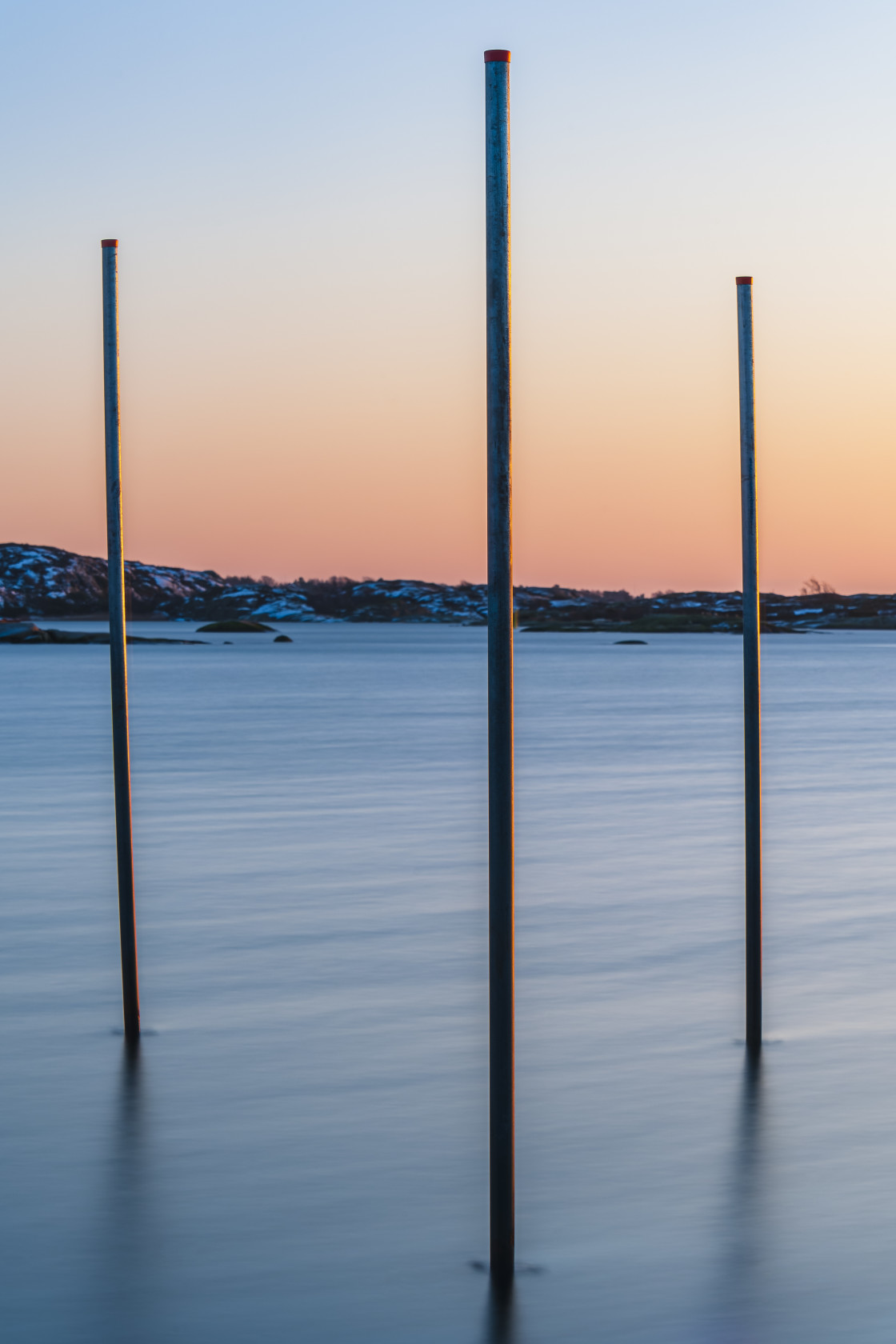 "Poles standing in sea at sunset" stock image