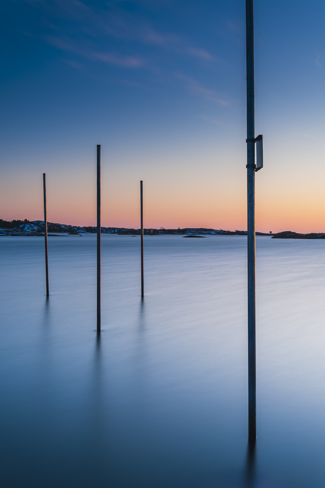 "Poles standing in sea at sunset" stock image