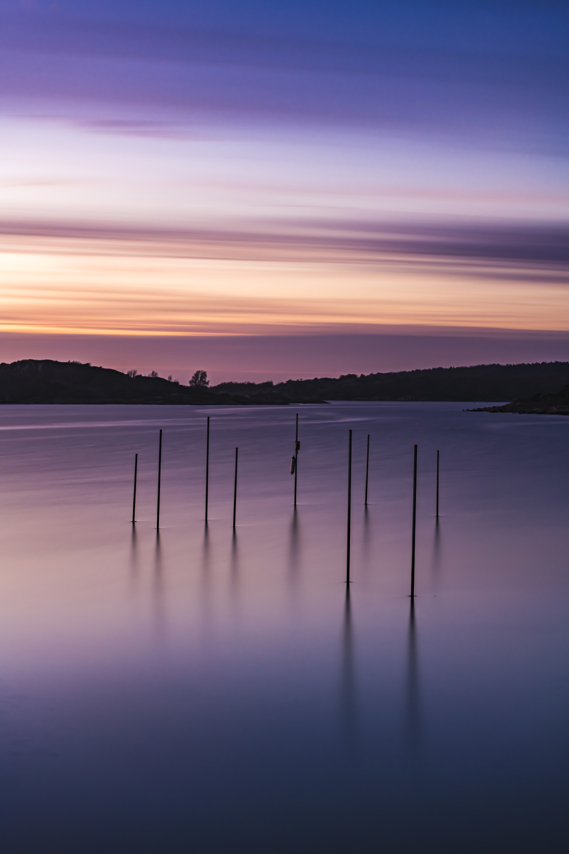 "Poles standing in sea at sunset" stock image