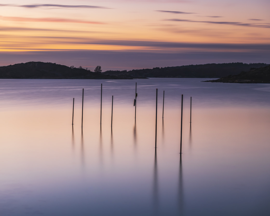 "Poles standing in sea at sunset" stock image