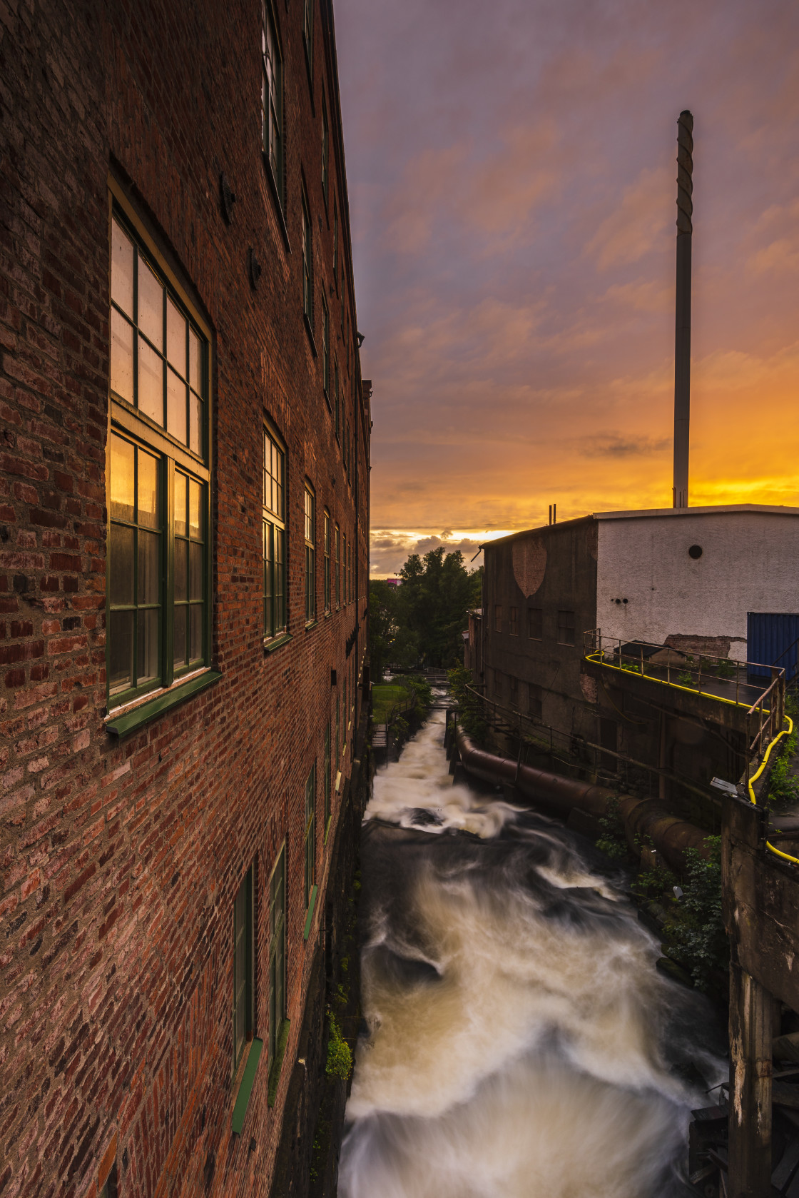 "Water flowing down besides old industry buildings" stock image