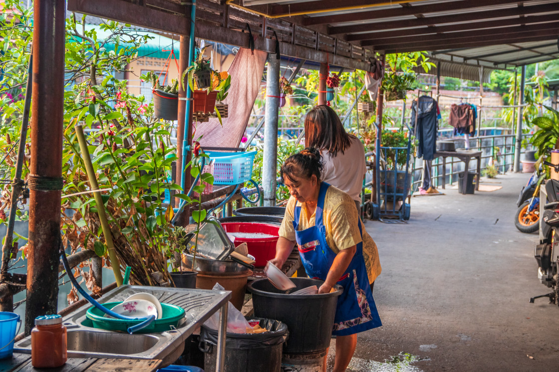 "Thai women clean or wash dishes on a path in a housing estate Pattaya District Chonburi in Thailand Asia" stock image