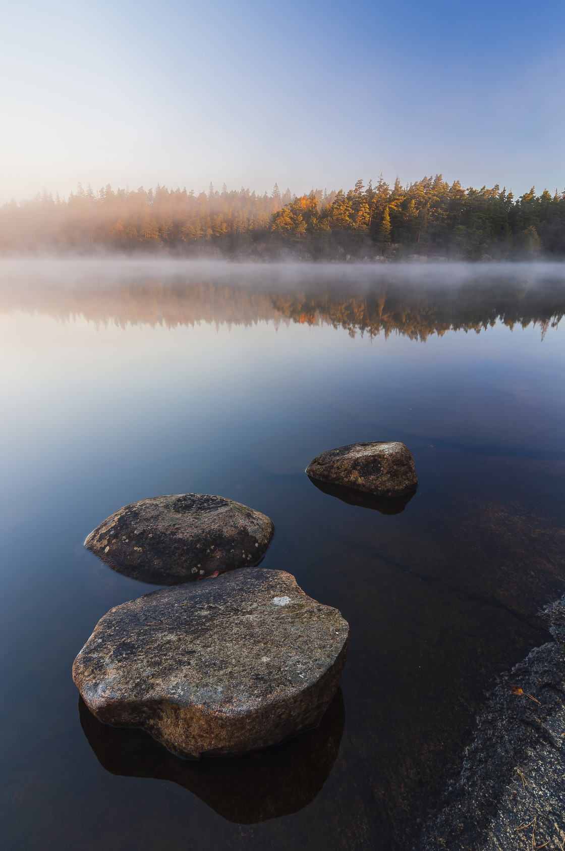 "Still lake with boulders at sunrise" stock image