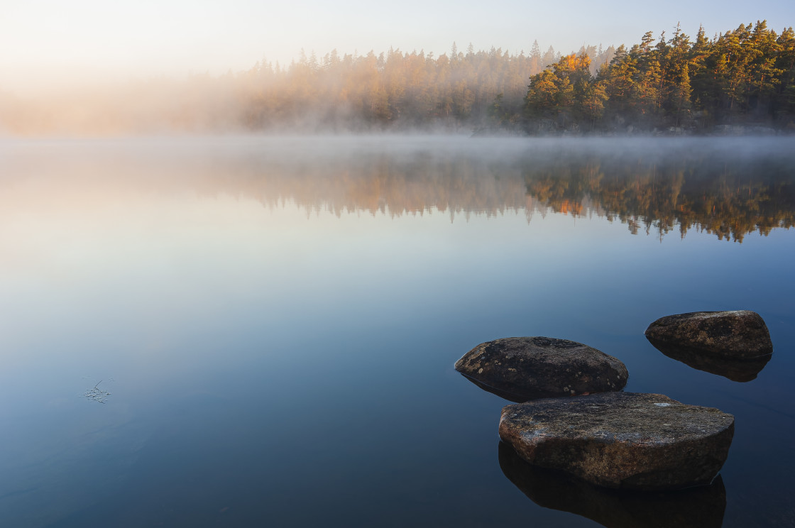 "Still lake with boulders at sunrise" stock image