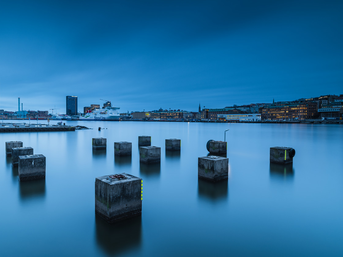 "A tranquil city waterfront scene captured during twilight with remnants of old pier pillars standing in the water." stock image