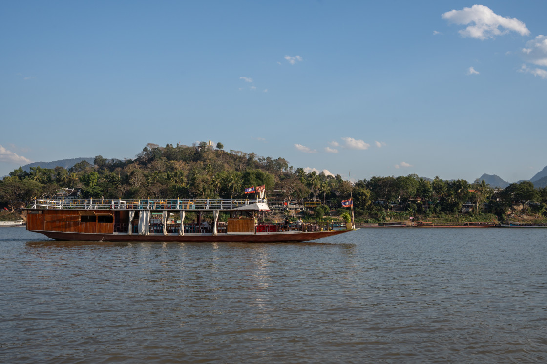 "A Laotian ferry boat carries motorcycles, scooters, assorted vehicles and passengers from one bank of the Mekong River to the other in Luang Prabang Laos Asia" stock image