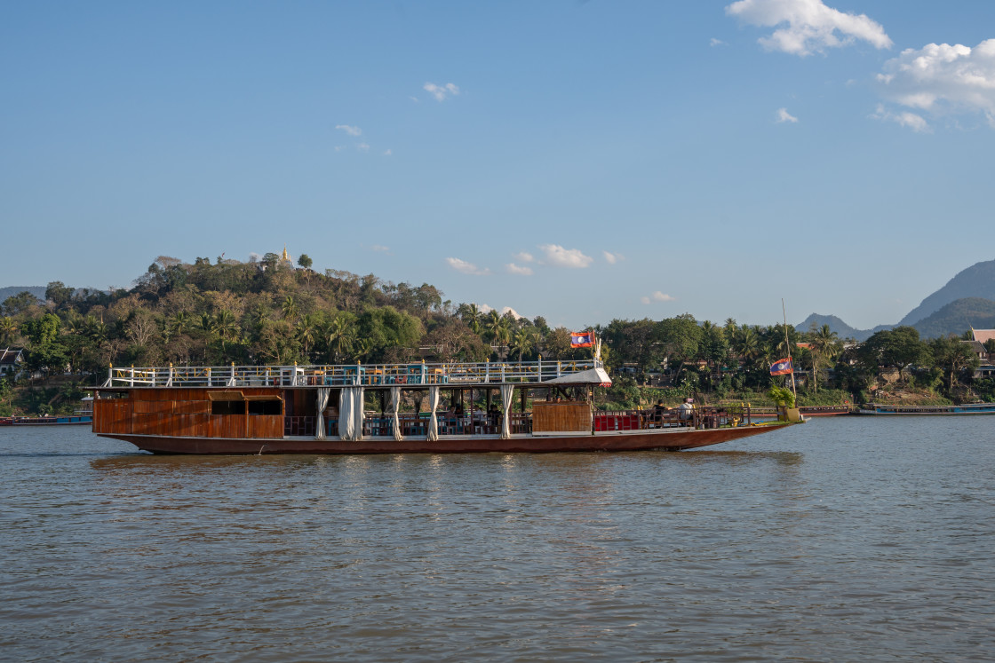 "A Laotian ferry boat carries motorcycles, scooters, assorted vehicles and passengers from one bank of the Mekong River to the other in Luang Prabang Laos Asia" stock image