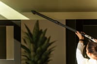 Showing Flexit black aluminium telescopic tube being used for vacuuming high areas near the ceiling