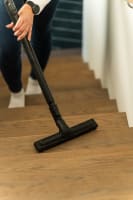 Showing a person vacuuming a staircase using a Flexit central vacuum floor nozzle