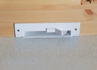 Floor sweep inlet installed in cabinet plinth for central vacuum, integrated in kitchen cabinetry