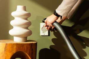 
                    Viser en person som kobler Flexit sentralstøvsugerslange til en veggmontert sugekontakt