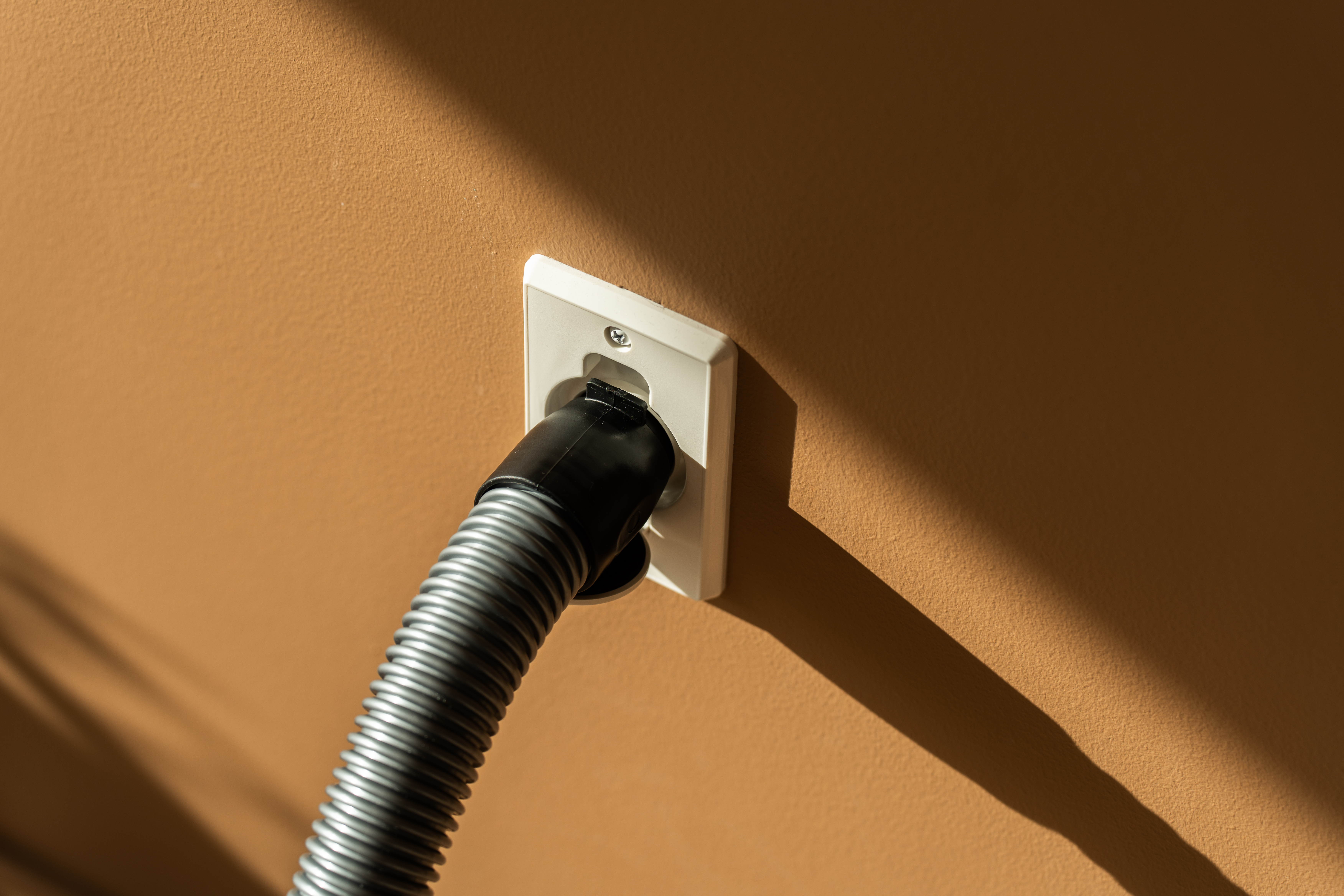 

                    Close-up of a central vacuum hose connected to a Flexit wall inlet valve