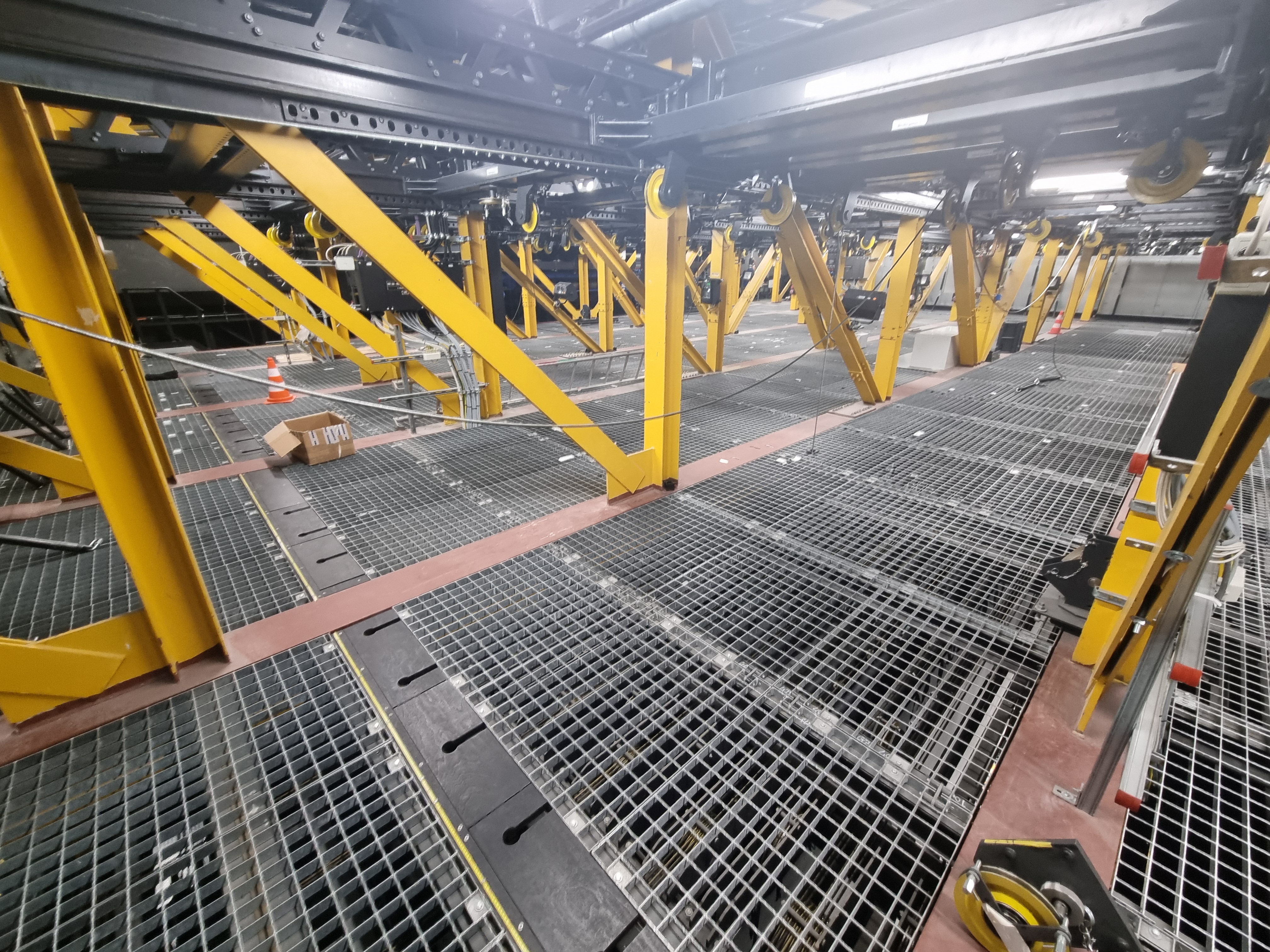 Yellow steel frames, overhead rails and grated walkways in the Berlin State Opera's stage machinery area.