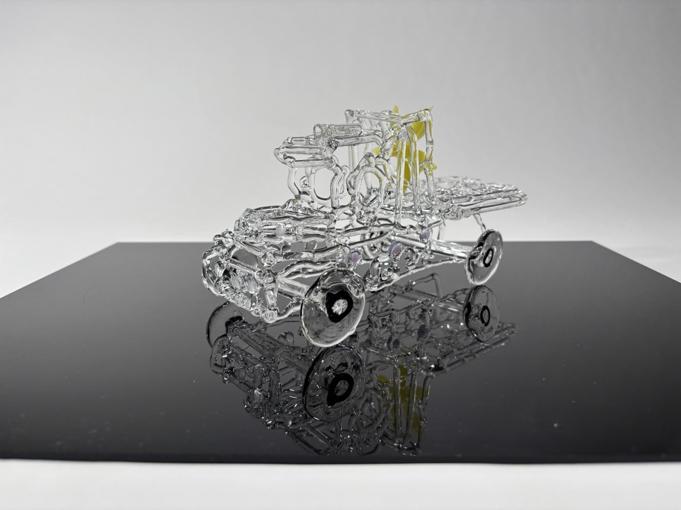 a model truck networked in glass with a yellow flower on the back of the cab, placed on a reflective panel