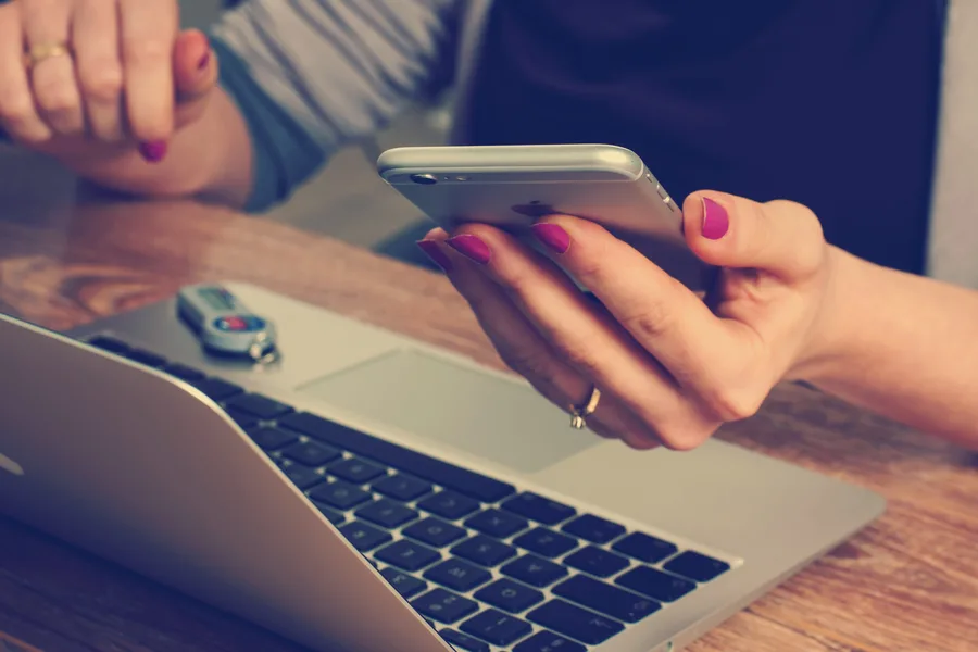 Person working on the computer while looking at cellphone