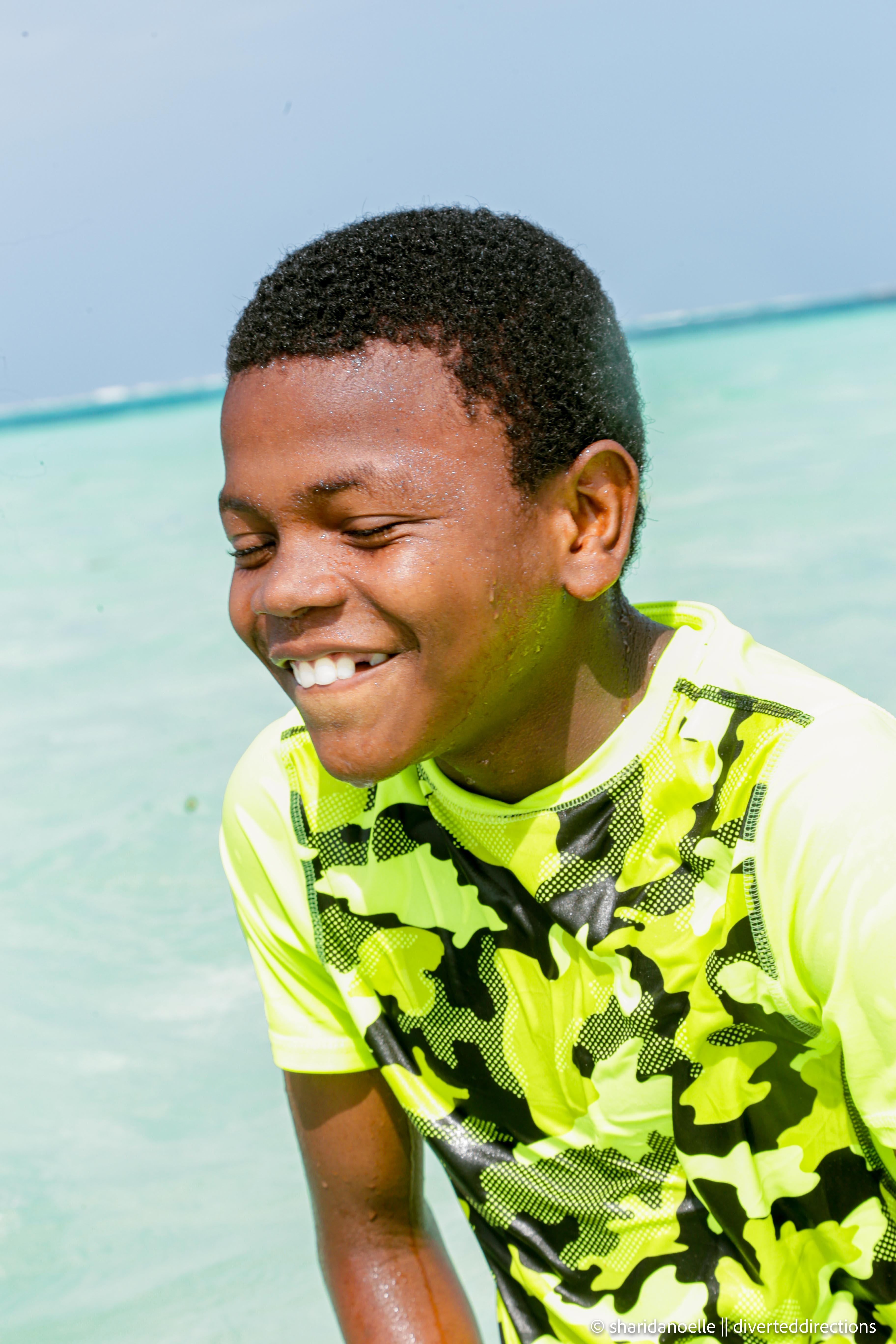 A boy smiling in the water, during the first swimming competition held by watoto school