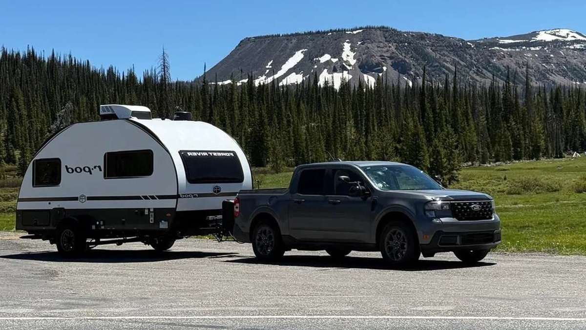 Ford Maverick towing a Forest River R-Pod travel trailer through a mountain landscape.