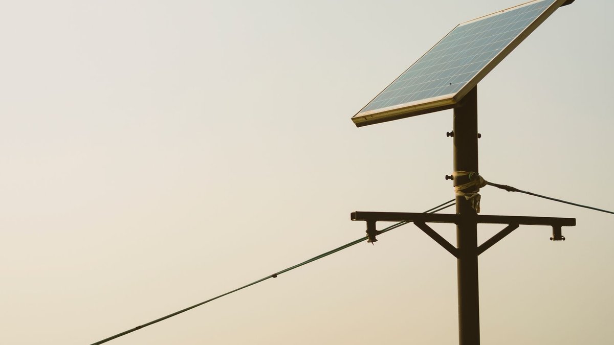 A single solar panel mounted on a tall post against a clear sky, symbolizing renewable energy.