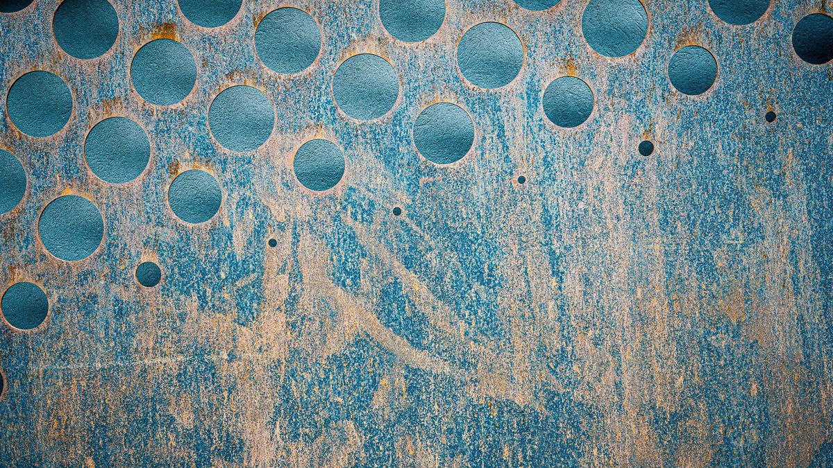 Doctors test gas-free macular hole surgery with strong results Textured backdrop of blue metallic wall with scratches and rusty round shaped holes.