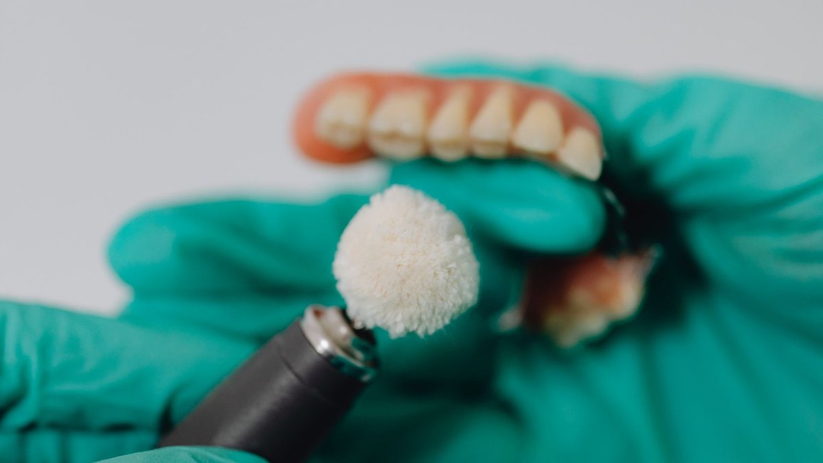 Detailed image of dentures being polished by a dental professional wearing gloves. Ideal for dental care topics.