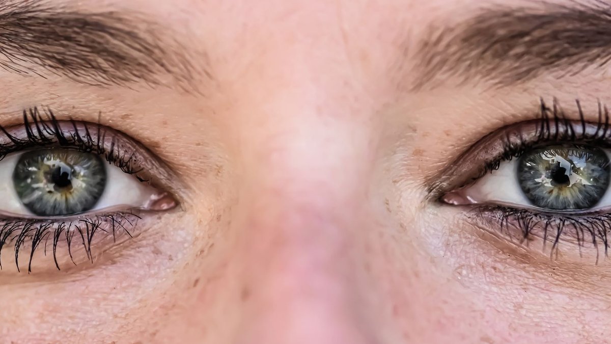 Detailed close-up of human eyes with reflections, showcasing lashes and eyebrows.