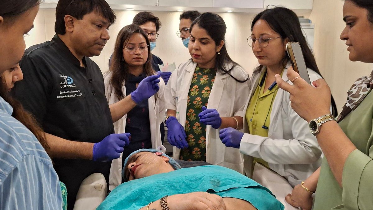 Dermatologists in training perform a procedure under supervision in a clinical setting.