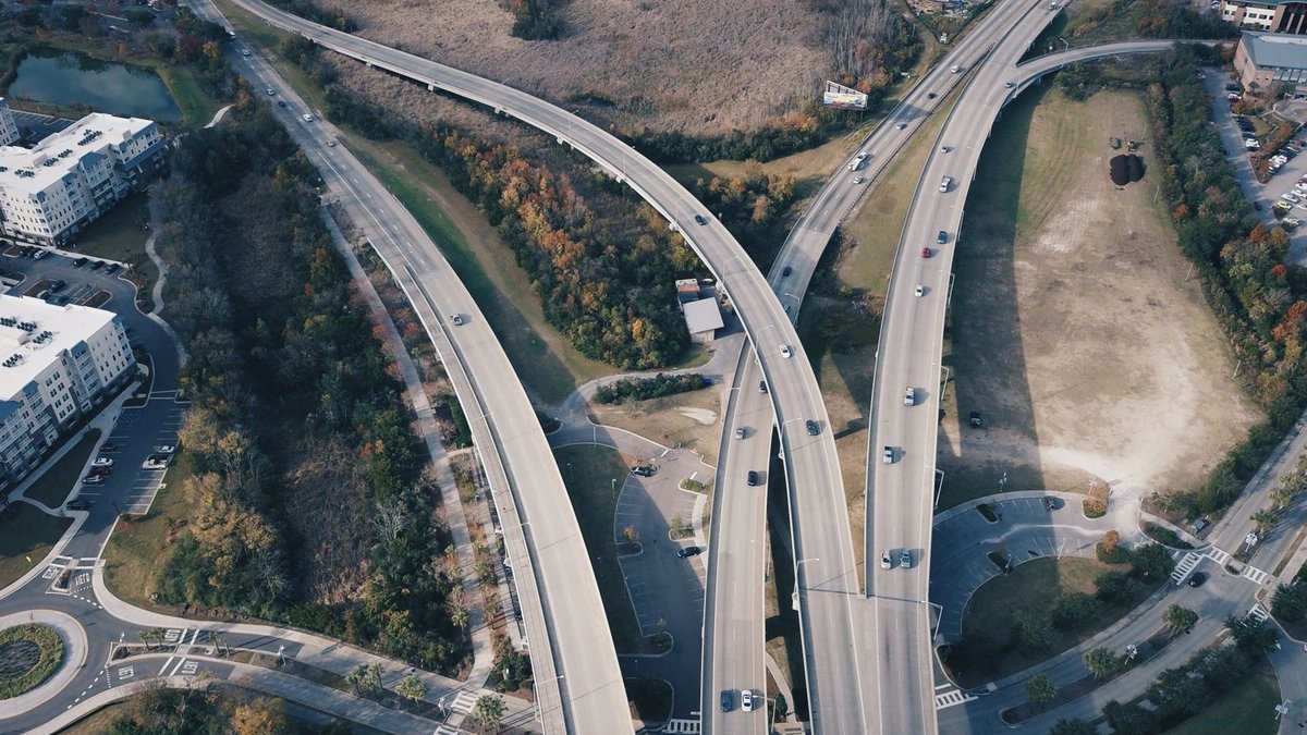 Aerial view of intersecting highways with light traffic and surrounding greenery.