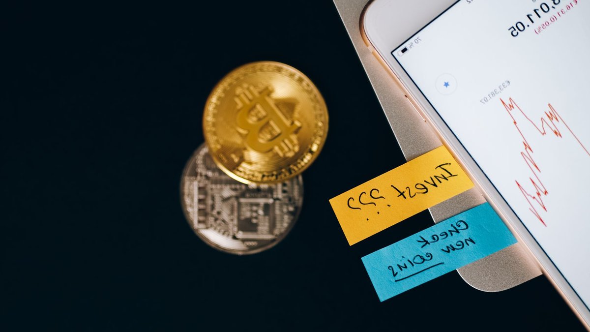 Schroders acquired by Nuveen to form $2.6tn manager Bitcoin coins and smartphone displaying price chart with investment notes.
