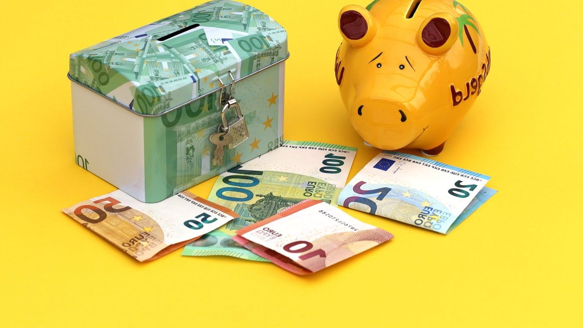 Yellow piggy bank and cash box with Euro notes on bright background.