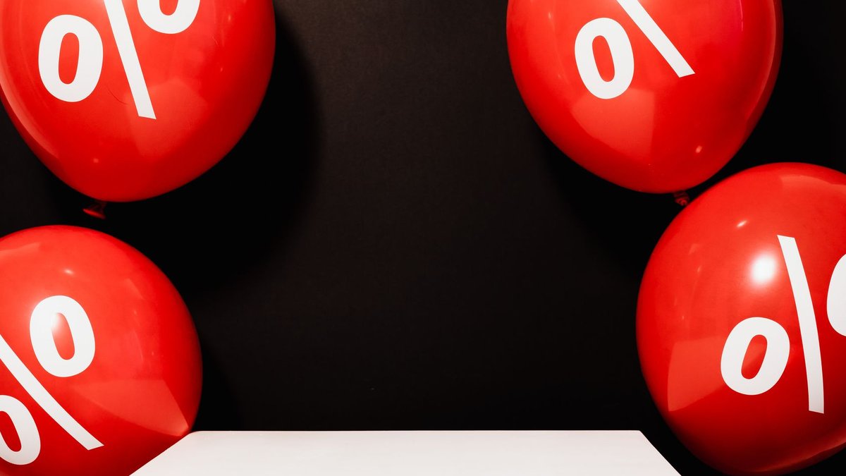 GTA home listings plunge while sales modestly decline Red balloons marked with percentage symbols on black background, perfect for sales promotions.
