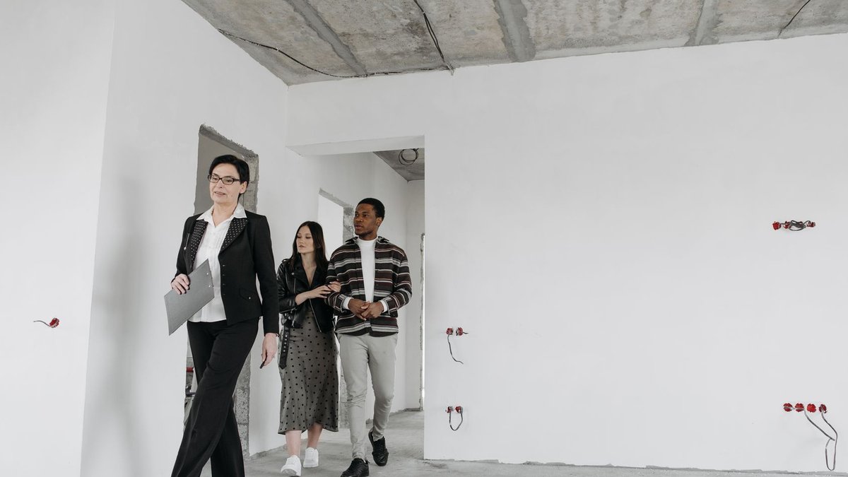 Real estate agent showing an unfinished house to potential buyers during a viewing session.