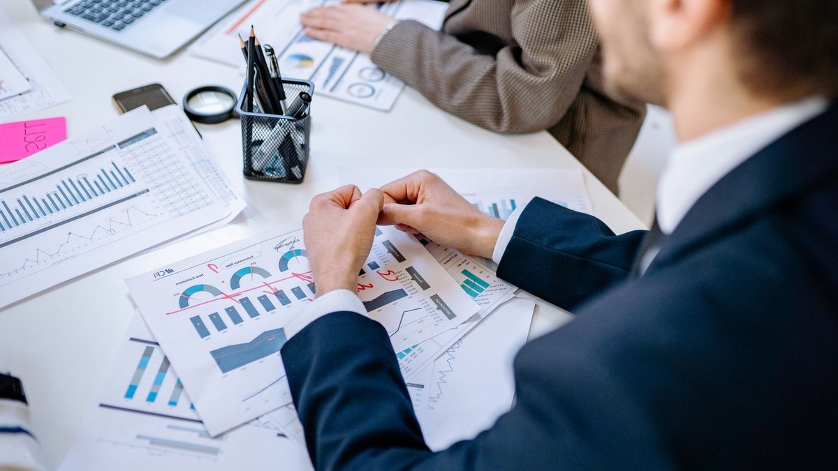 Business team analyzing financial graphs at a meeting table, fostering collaboration in an office environment.