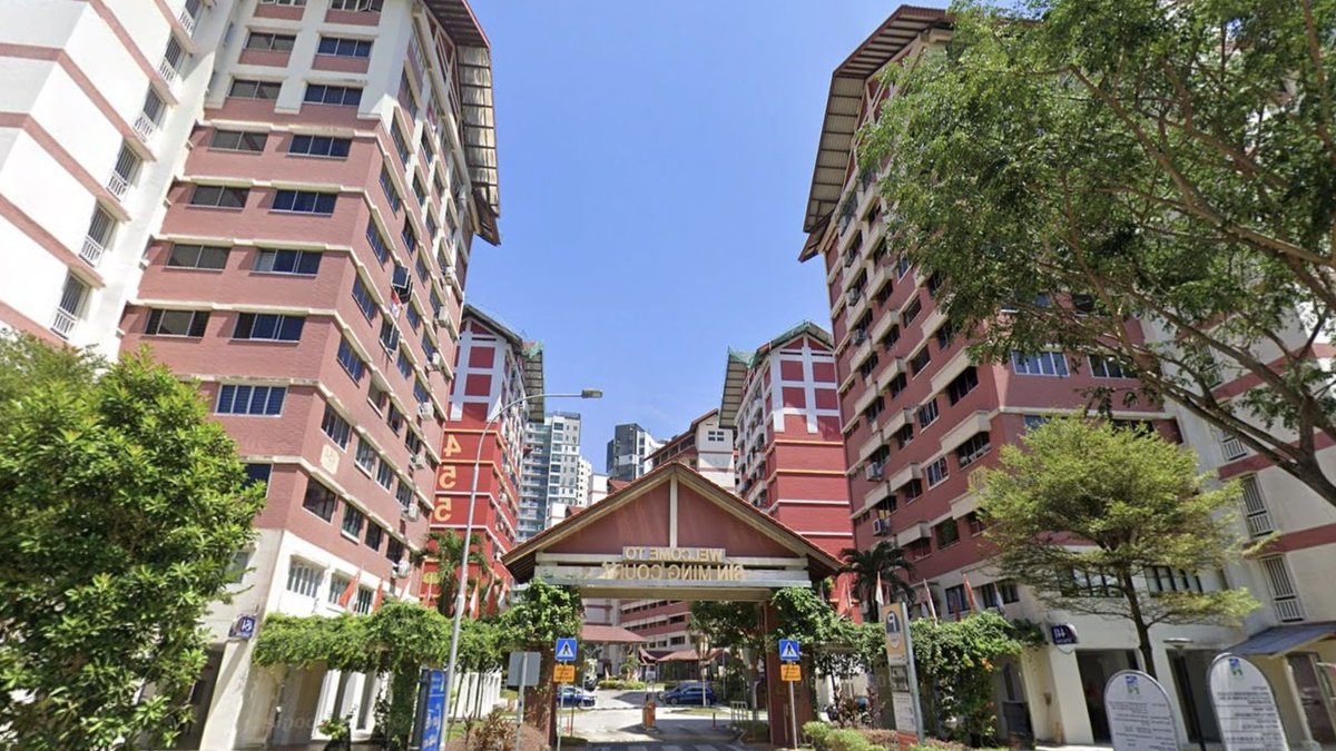 Bishan HDB flat sets new price record Bin Ming Court residential blocks with a central entrance gateway and trees under a clear blue sky.