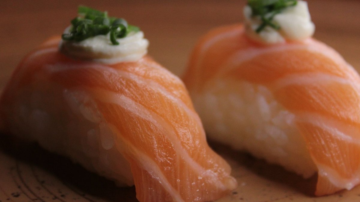 A beautiful close-up of two salmon nigiri sushi pieces garnished with wasabi and green onions.