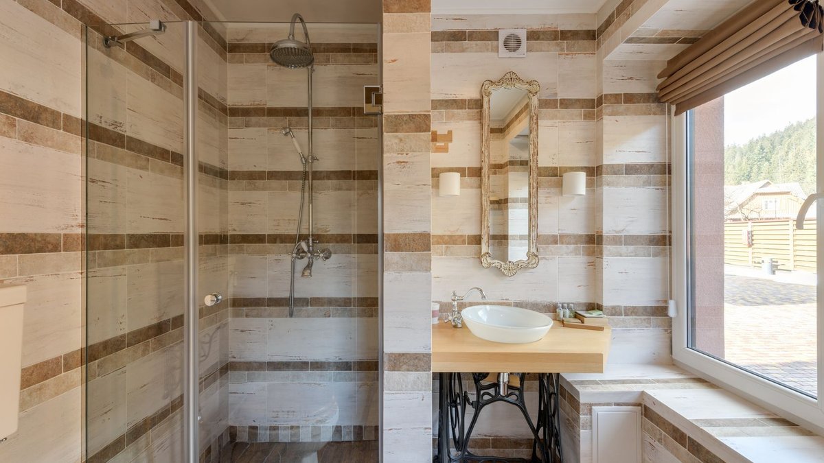 A stylish bathroom featuring a rustic vanity and a glass shower with natural light.