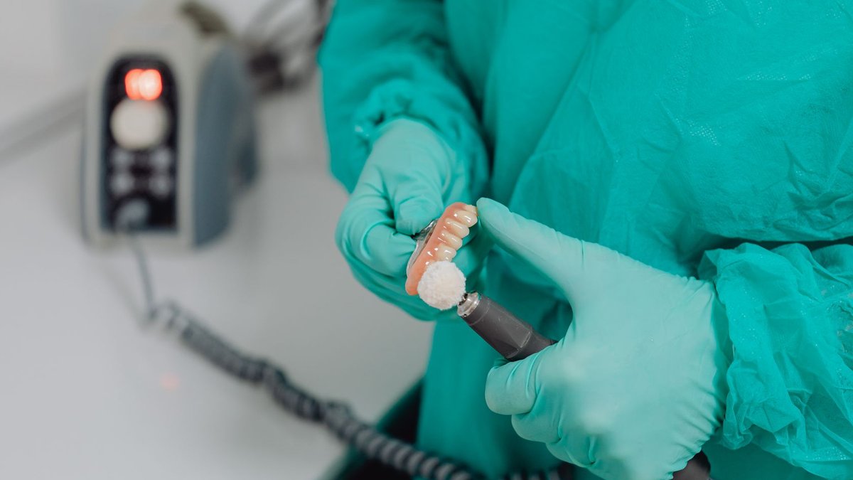 Close-up of a dentist polishing dentures with precision in a sterile clinic.