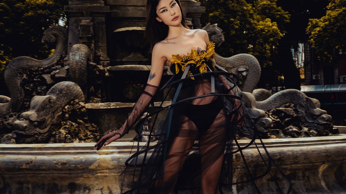 Fashion model posing by ornamental fountain in unique dress.