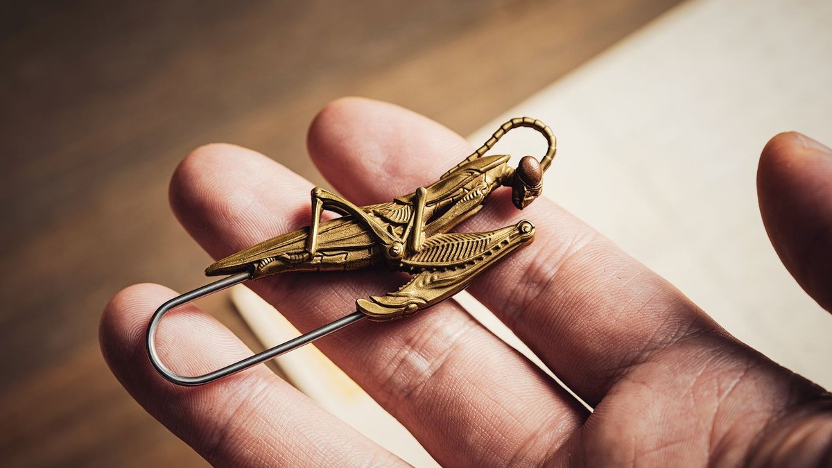 Mantis Collection Opens First Resort in Saudi Arabia's Al Baha Detailed close-up of a unique mantis-shaped brass clip held in a person's hand.