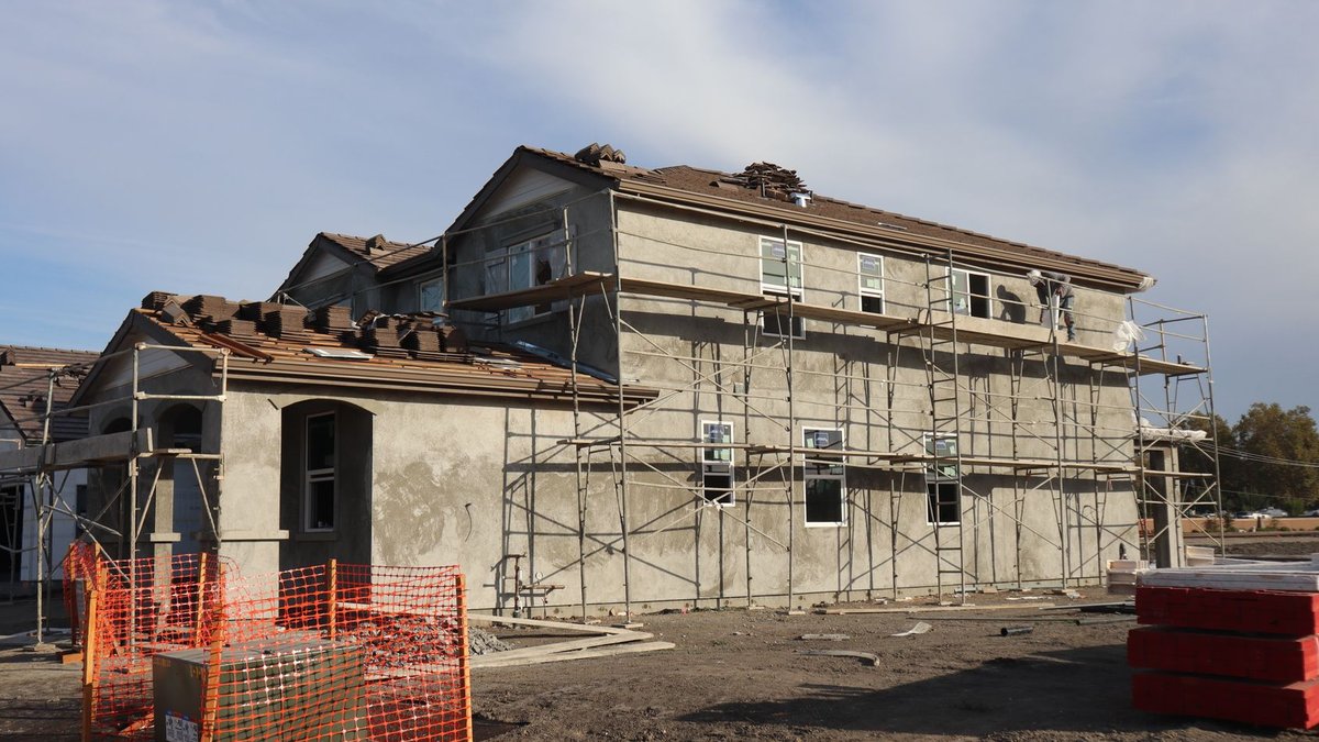 Saskatchewan Housing Supply Up, But Still Below Average Two-story residential building under construction, featuring scaffolding and roof tiles.