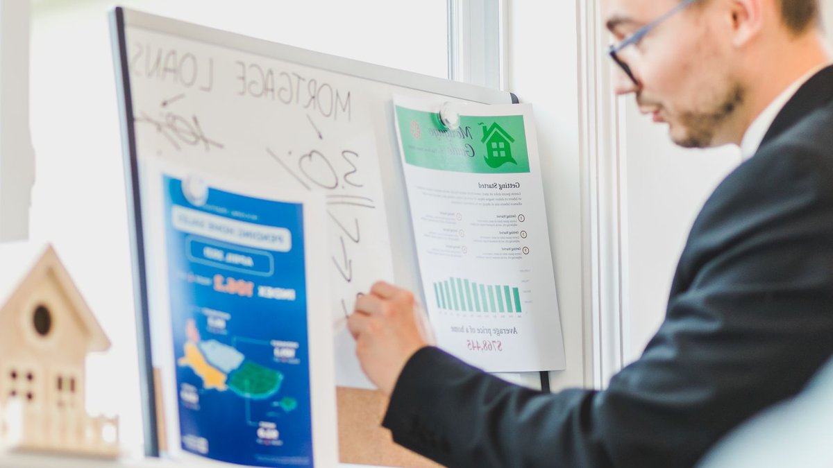 Court allows commission lawsuit to proceed Real estate agent analyzing mortgage loan details on a whiteboard in an office setting.