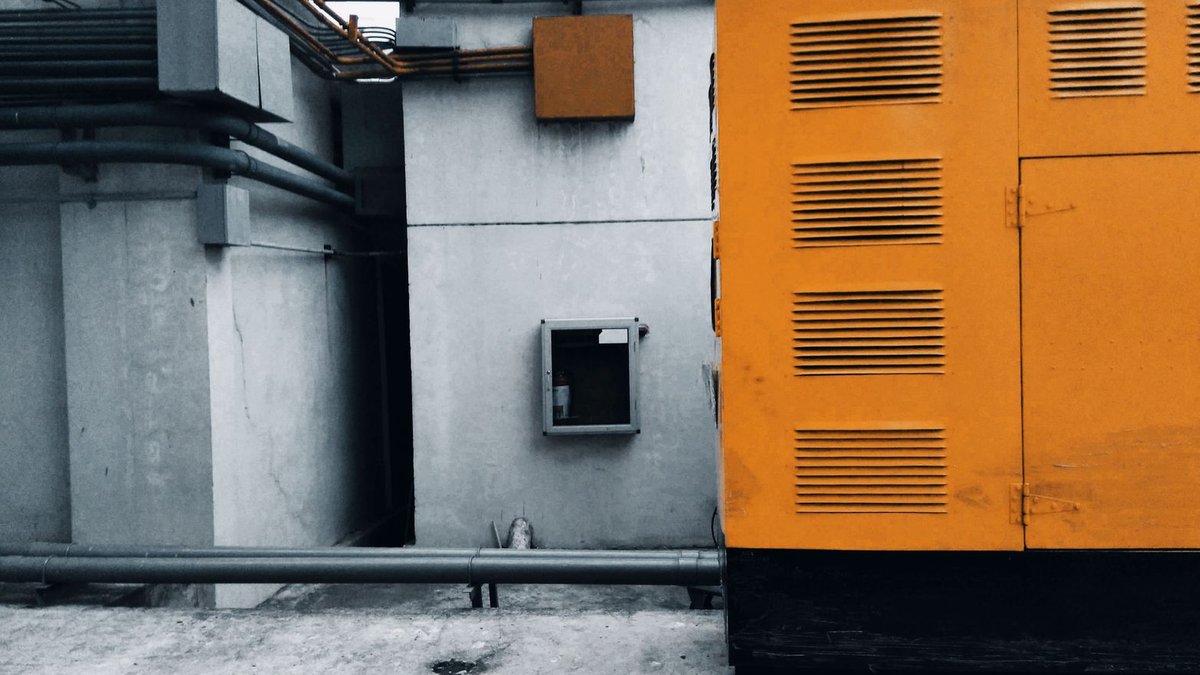 Amazon discounts generators up to 40 percent Outdoor view of an industrial generator with visible piping and wiring against a concrete wall.