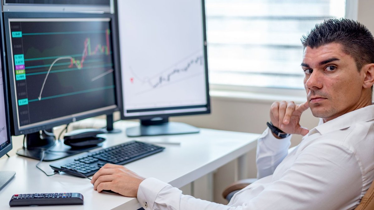 CHAT and THNQ AI ETFs Contrast in Strategy and Performance Professional stock market analyst monitoring data on multiple screens at a workstation.