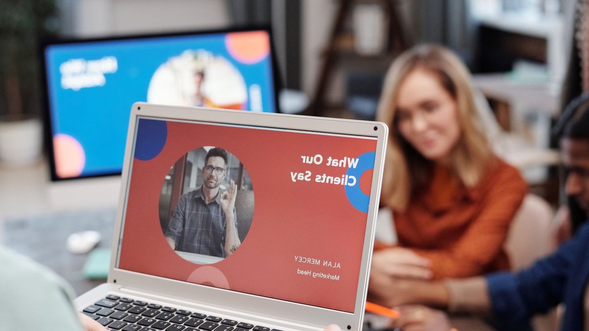Acorns acquires Frich Money adds Gen Z focus Diverse business team in a meeting analyzing client testimonial on laptop screen.
