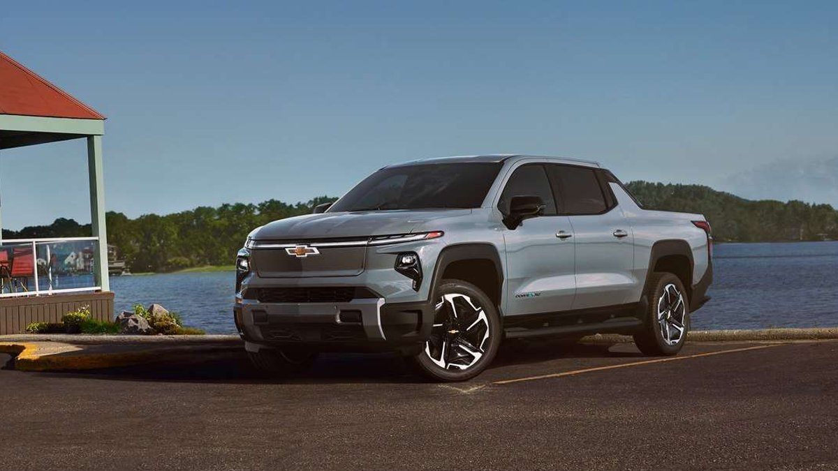 Slate Gray 2025 Chevrolet Silverado EV LT parked beside a lake, shown from the front three-quarter angle.