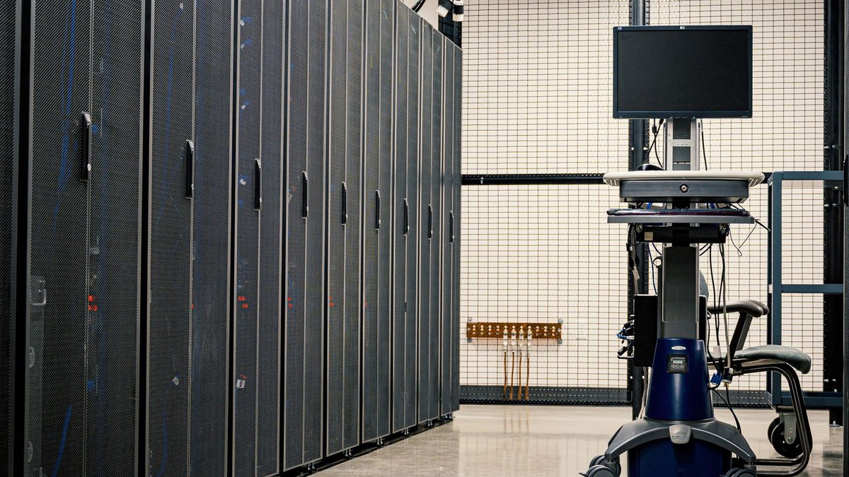 Contemporary computer on support between telecommunication racks and cabinets in modern data center.