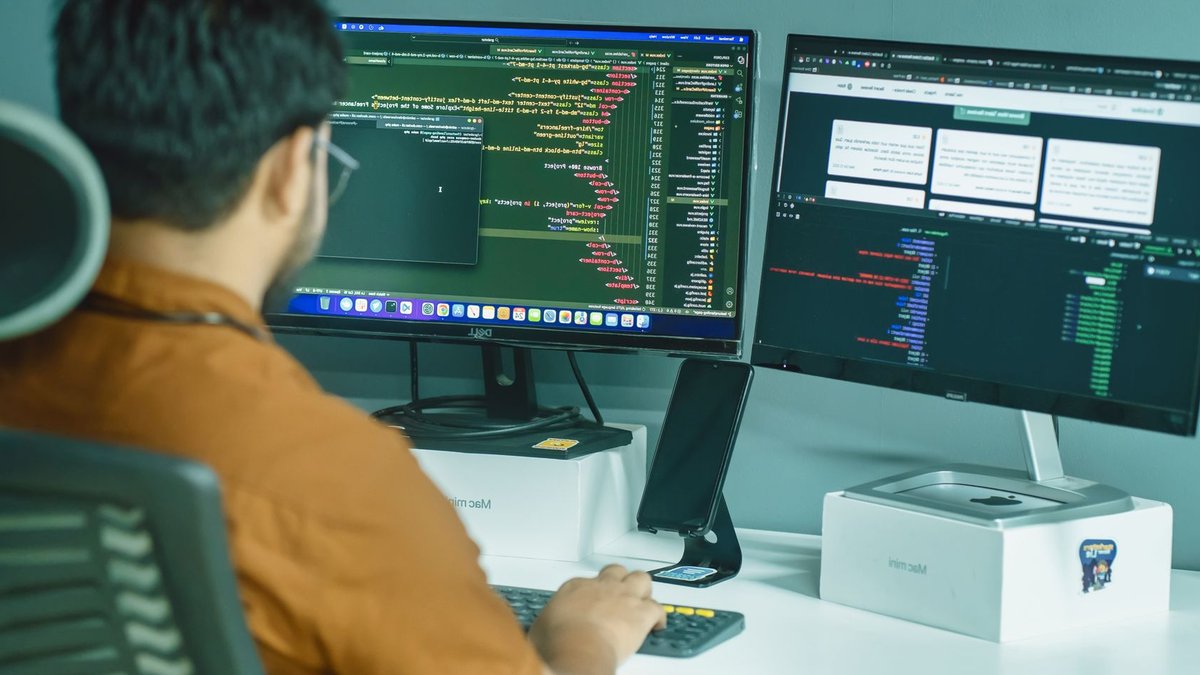 Infosys profit may rise 10 percent A software developer engaged in coding on dual monitors in a modern office setting.