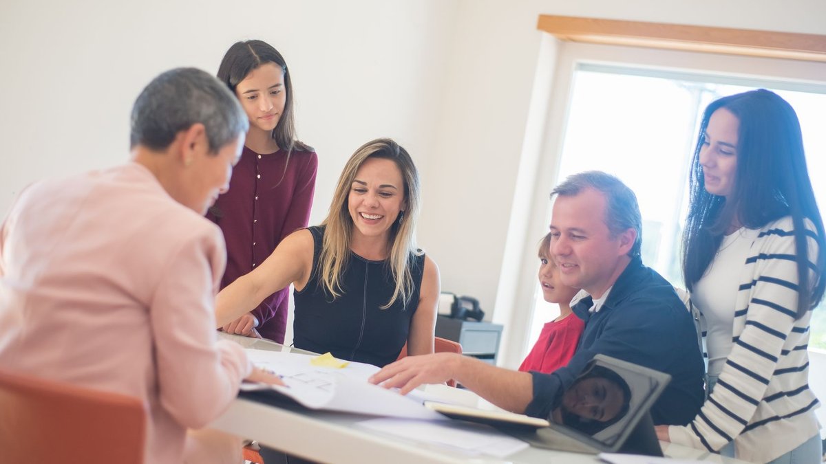 A happy family gathering around a desk during a home meeting, discussing documents.