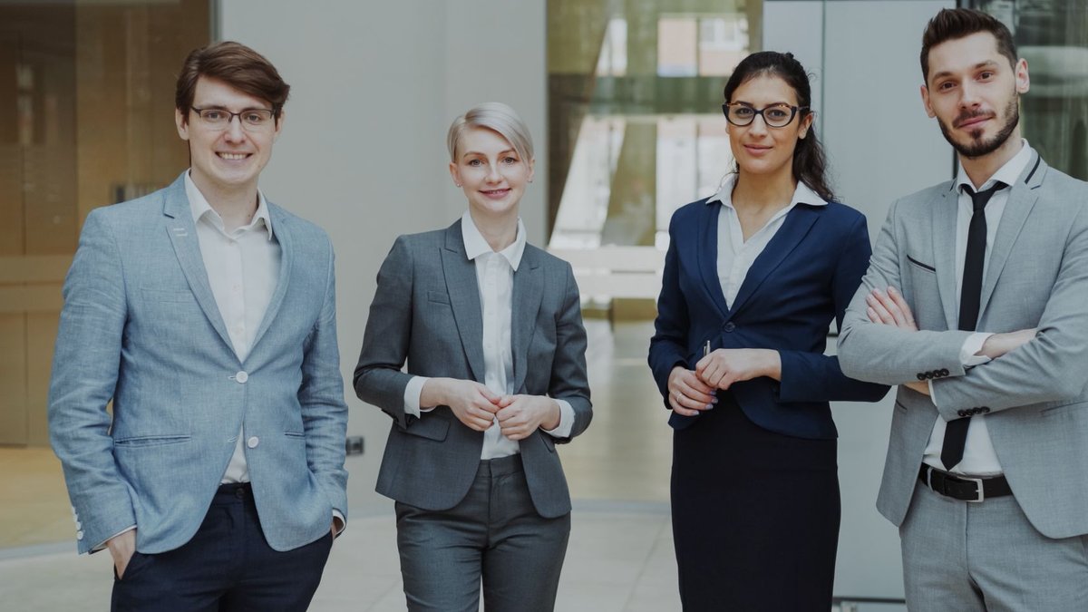 Environment industry hosts major hiring event amid worker shortage Four business professionals posing confidently in a modern office environment.