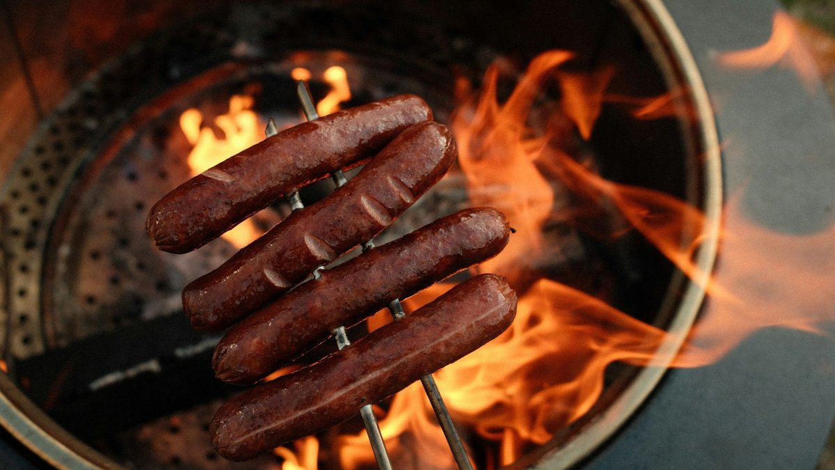 Hot dogs cooking over an open fire.