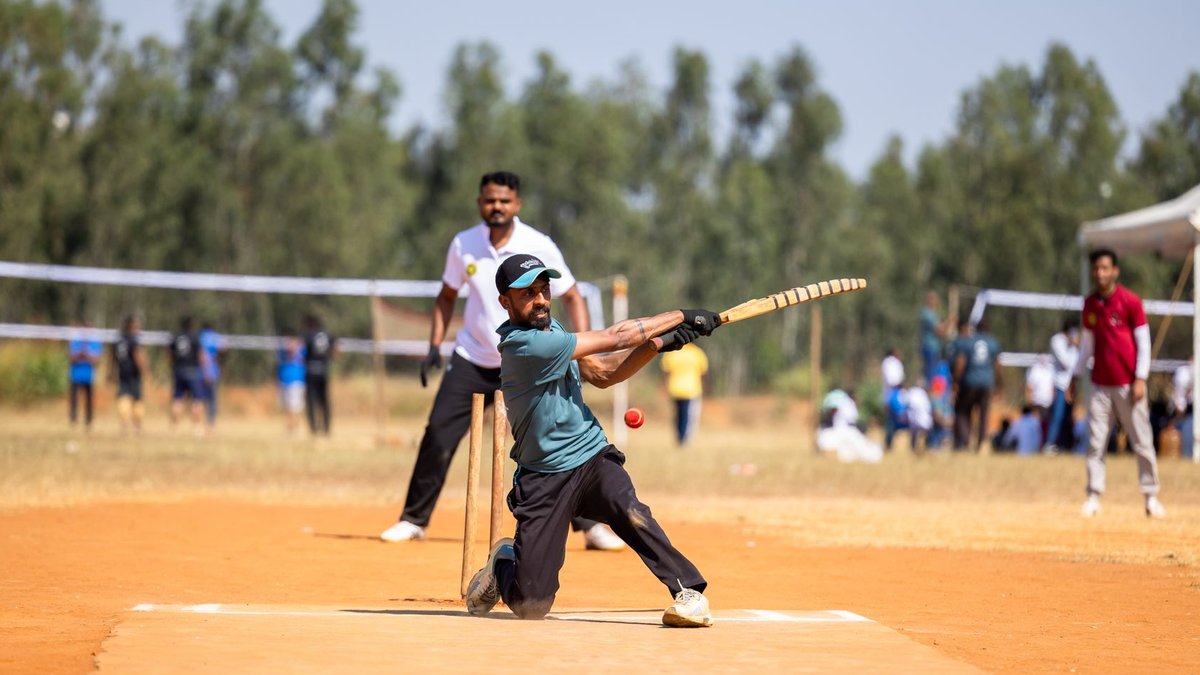 Cricket player skillfully hitting a ball during a lively outdoor match on a sunny day.